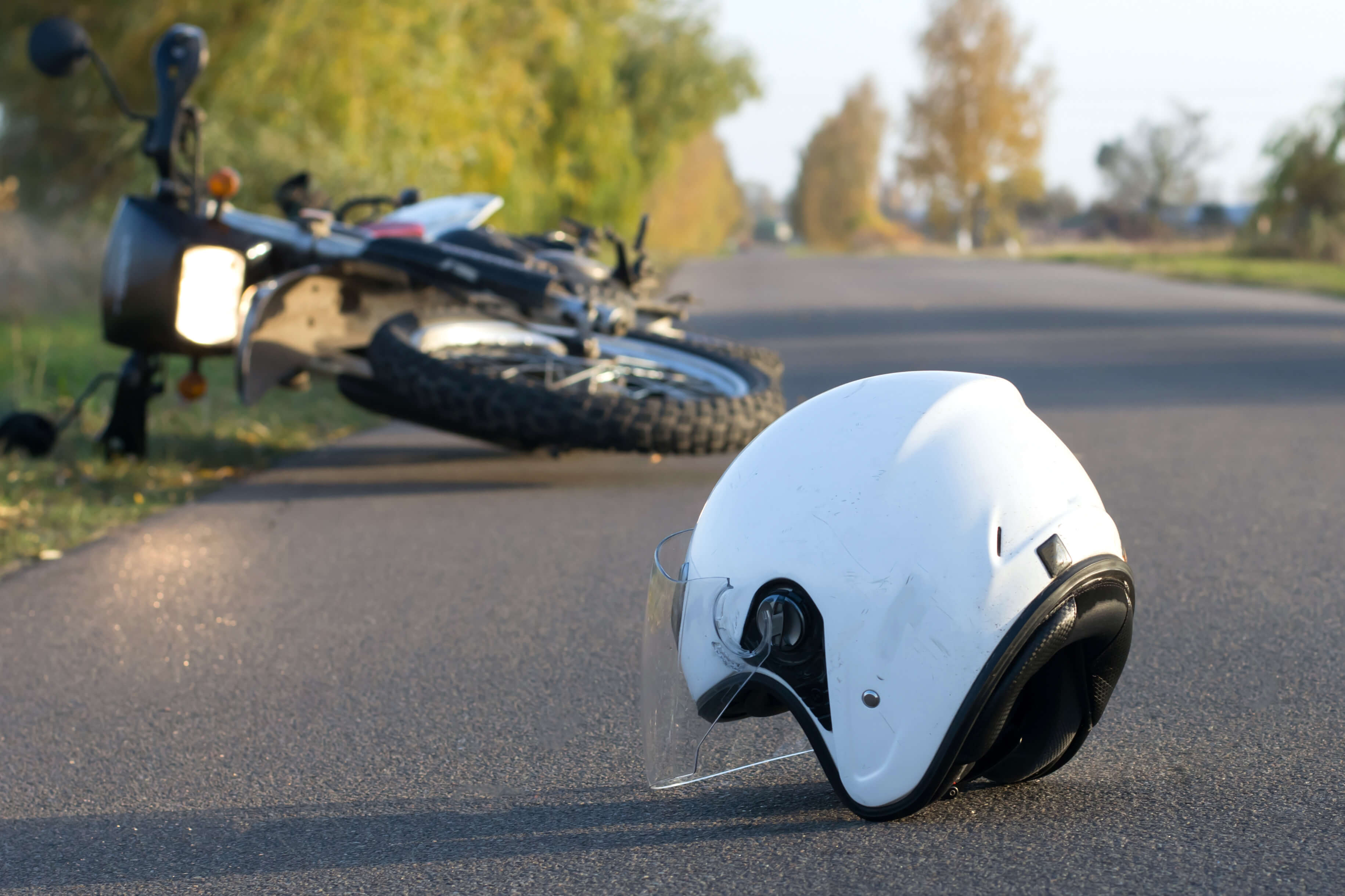 white helmet on asphalt next to overturned motorcycle